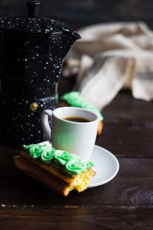 Cup of coffee and eclair on dark wooden table with copyspaceの写真素材