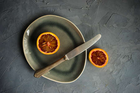 Slices of organic red orange fruit on beautiful ceramic plate with copy spaceの写真素材