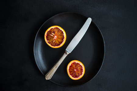 Slices of organic red orange fruit on beautiful ceramic plate with copy spaceの写真素材