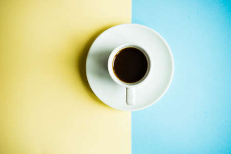 Coffee concept with cup of coffee on yellow and blue background with copy spaceの写真素材