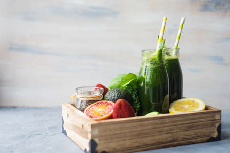 Organic and healthy green smoothie with banana, spinach, avocado, citrus fruits and chia seeds in a glass bottles on a rustic background withcopy spaceの写真素材