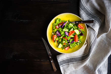 Oraganic vegetable salad with lettuce, cucumber, cherry tomatoes and flax seeds on rustic background with copy spaceの写真素材