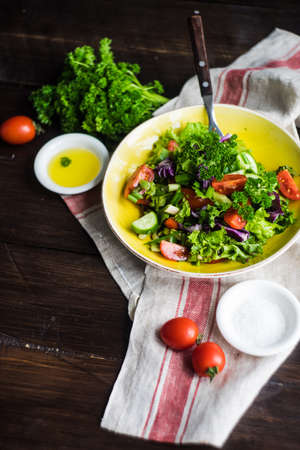 Oraganic vegetable salad with lettuce, cucumber, cherry tomatoes and flax seeds on rustic background with copy spaceの写真素材