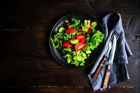 Oraganic vegetable salad with lettuce, cucumber, cherry tomatoes and flax seeds on rustic background with copy spaceの写真素材