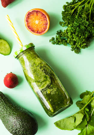 Organic and healthy green smoothie with banana, spinach, avocado, citrus fruits and chia seeds in a glass bottles on green background withcopy spaceの写真素材