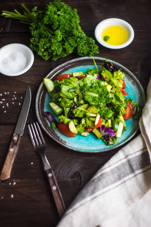 Oraganic vegetable salad with lettuce, cucumber, cherry tomatoes and flax seeds on rustic background with copy spaceの写真素材