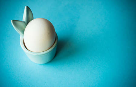 Boiled egg in bunny egg cup on blue background with copy spaceの写真素材