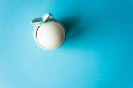 Boiled egg in bunny egg cup on blue background with copy spaceの写真素材