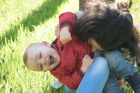 Mom and little baby boy playing outdoor together in a spring time park