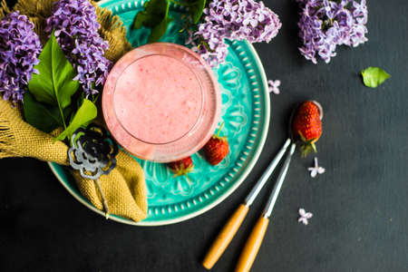 Spring dessert ice cream with strawberry cocktail on rustic table decorated with lilac flowersの写真素材