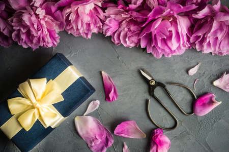 Gift box concept with pink peony flowers on rustic background with copy space
