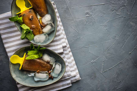 Summer dessert concept coffee lollypops with mint and ice on rustic background with copy space