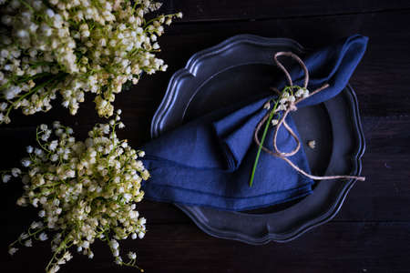 Spring table setting with may lily on dark wooden table with copy space