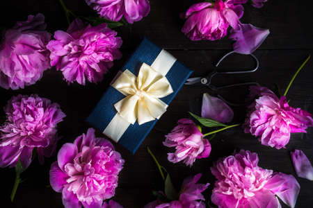 Gift box concept with pink peony flowers on rustic background with copy spaceの写真素材