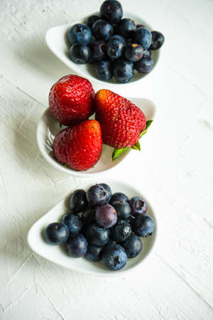 Summer fruit dessert with blueberries and strawberries on white concrete backgroundの写真素材