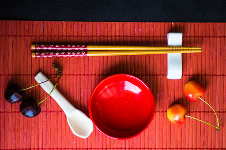 Table setting in red color for asian cuisine dinner with chopsticksの写真素材