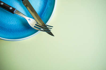 Rustic table setting with blue plate and silverware on yellow backgroundの写真素材