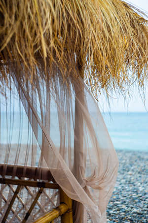 Beach bungalow with straw roof on a coast in sunset timeの写真素材