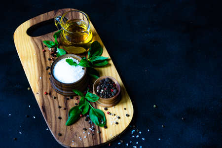 Cooking concept with spices, oil and basil herb on dark background with copy spaceの写真素材