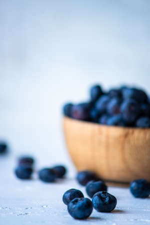 Blue berries in a bowl on white concrete background with copy space