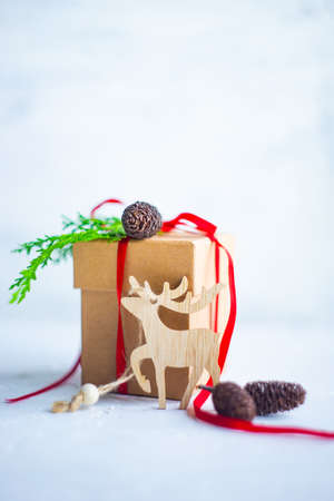 Christmas festive card concept with gift box decorated with red ribbon, balls, cones and fir tree branch on white background with copy spaceの写真素材