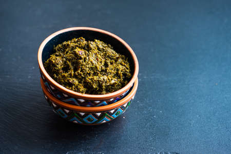 Traditional georgian sauce adjika in ceramic bowl on rustic background with copy space