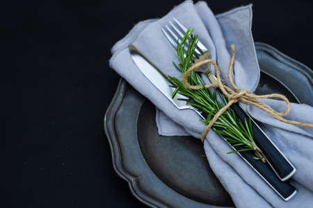 Rustic table setting with rosemary herb on dark wooden background with copy spaceの写真素材