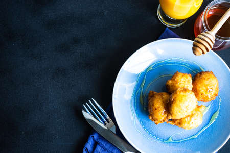 Homemade honey donuts on ceramic plate with honey and orange juice as a breakfast conceptの写真素材