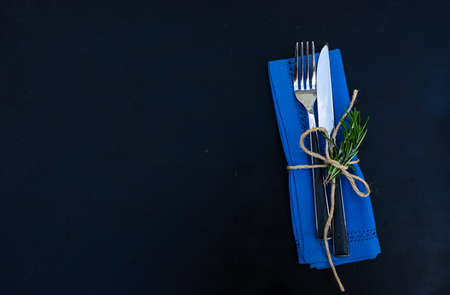 Rustic table setting with rosemary herb on dark wooden background with copy space