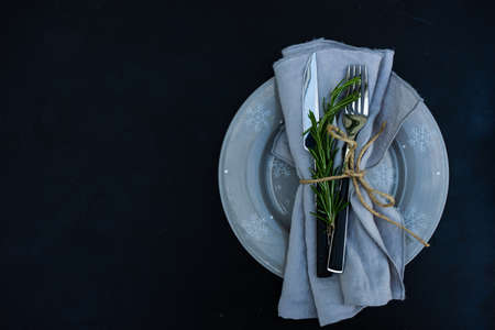 Rustic table setting with rosemary herb for Christmas dinner on dark wooden background with copy...