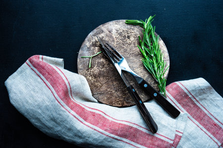 Table setting with vintage cutting board and cutlery decorated with rosemary herbの写真素材