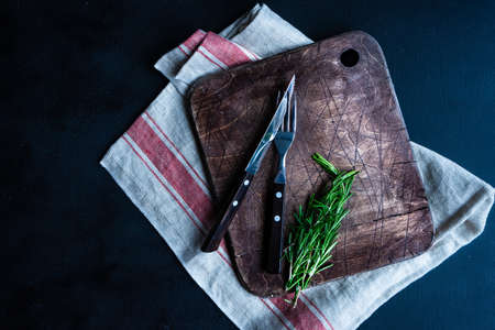 Table setting with vintage cutting board and cutlery decorated with rosemary herbの写真素材
