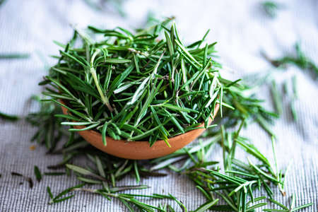 Rustic bowl full of rosemary herb on textile backgroundの写真素材