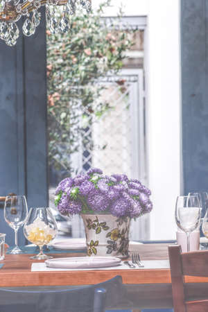 Autumnal table setting with flat ceramic plates and wine glasses on rustic table decorated with...