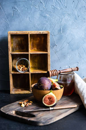 Autumnal ripe fig fruits in woode bowl with honey and huts as a seasonal food conceptの写真素材