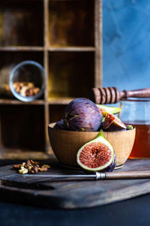 Autumnal ripe fig fruits in woode bowl with honey and huts as a seasonal food conceptの写真素材