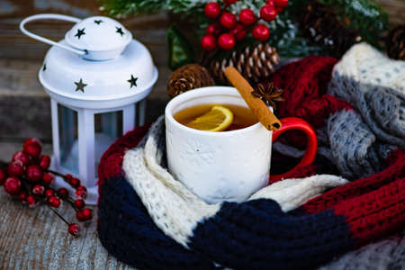 Cup of tea with lemon and winter spices like cinnamon and anise star on dark wooden background