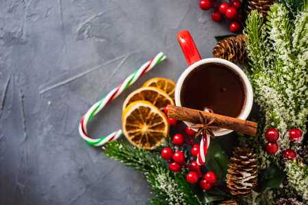 Christmas cocoa drink with cinnamon stick and sweet cone on rustic background with copy space