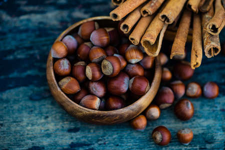 Organic food concept with bowl full of nuts and cinnamon sticks on vintage wooden background