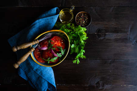 Ceramic bowl full of salad of organic vegetables like a tomato, red onion, rocket herb and flax seed on dark wooden table with copy spaceの写真素材