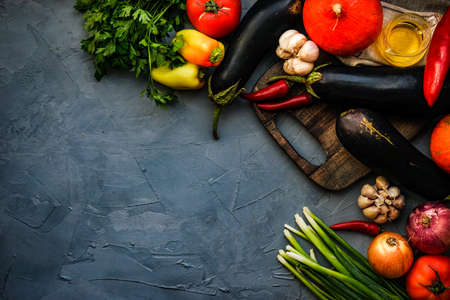 Frame with organic fresh vegetables like eggplant, tomato, herbs etc on rustic background with copy spaceの写真素材