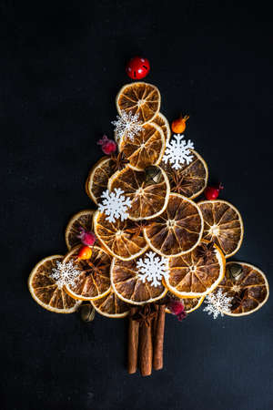 Christmas holiday concept with oranges and cinnamon  shaped in Christmas tree on dark wooden...