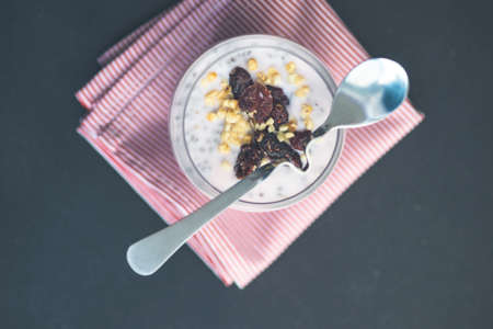 Organic chia seeds pudding with nuts and cherry on rustic background with copy space