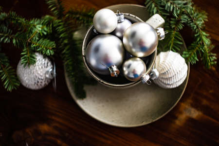 Festive table setting with ceramic plate and cup full of vintage balls on wooden backgroundの写真素材