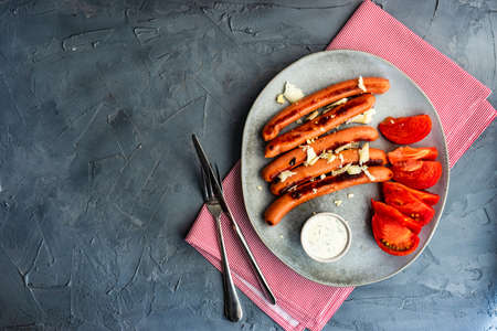 Traditional german food - sausages, cheese and tomatoes with sour cream garlic sauce on rustic backgroundの写真素材