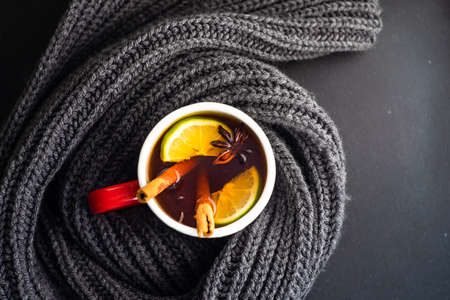 Winter hot mulled tea with lemon and spices and warm knitted scarfの写真素材
