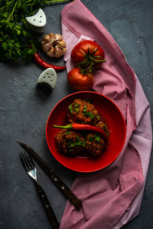 Meatballs in spicy tomato sauce with coriander and garlic on rustic table