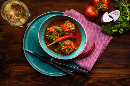 Meatballs in spicy tomato sauce with coriander and garlic on rustic tableの写真素材
