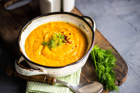 Tasty pumpkin soup in bowl on rustic background with copy space