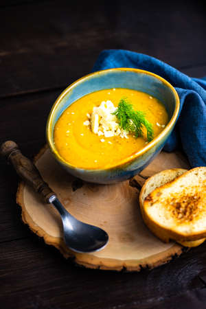 Autumnal food concept with bowl of tasty cream soup on rustic background with copy space